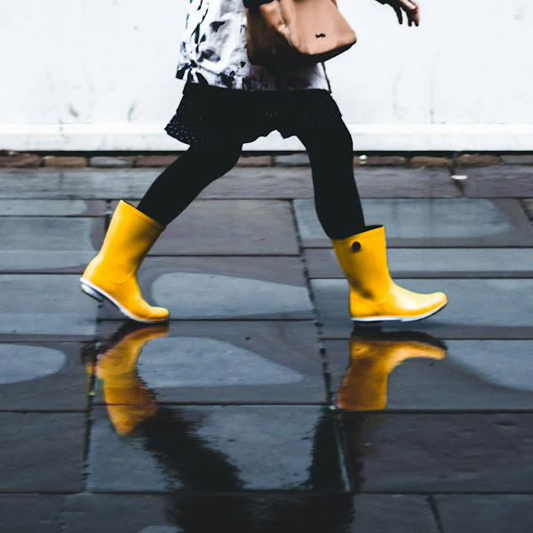 person walking with focus on yellow rain boots